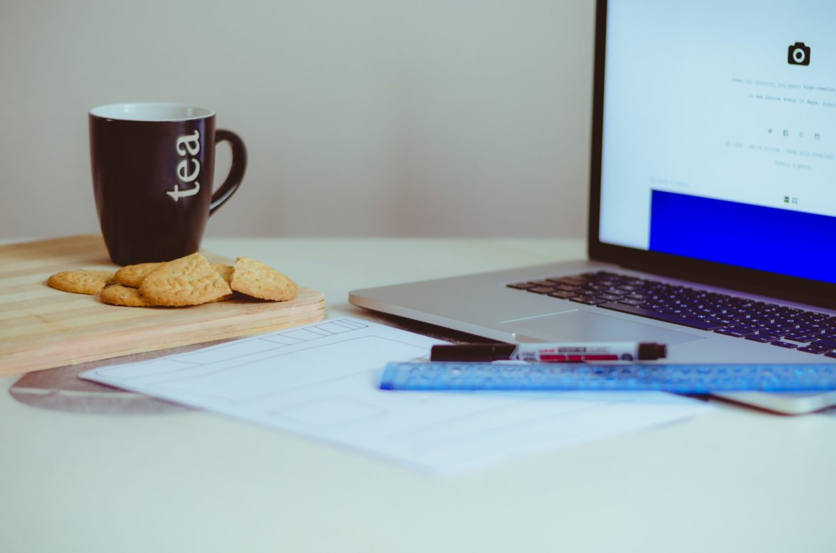 cup of tea and cookies on a table next to a computer