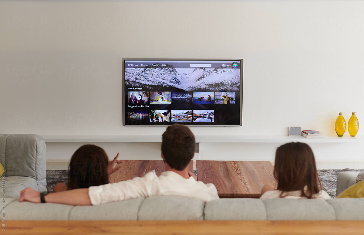 two women and a man sitting on a couch watching tv