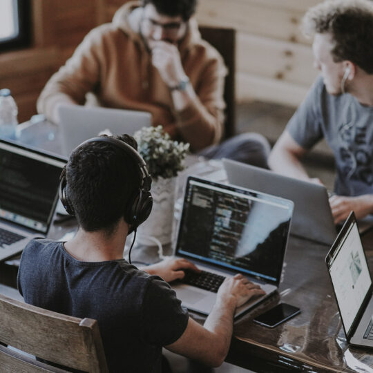 people sitting at a table working on laptops to show Client Audit Logs