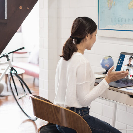 Woman sitting at a desk in her home talking to people on her laptop as a response to COVID-19