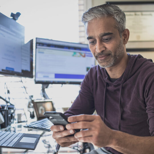 Man sitting at his desk looking at his phone