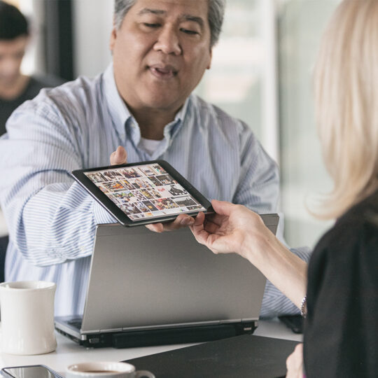 Photo d'un homme tendant une tablette à une femme dans un bureau