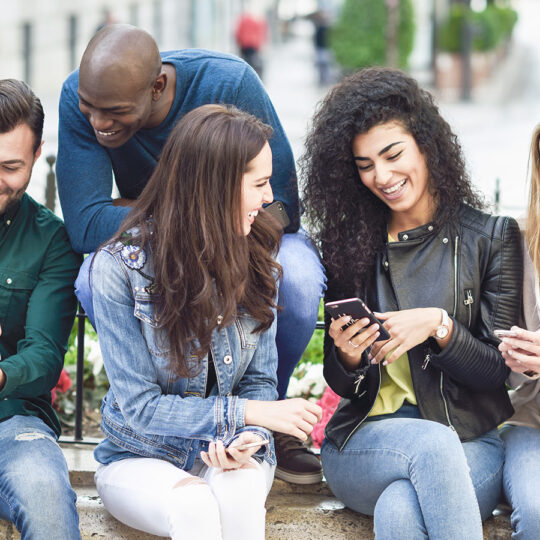 Young group of people looking at their phones and tablet