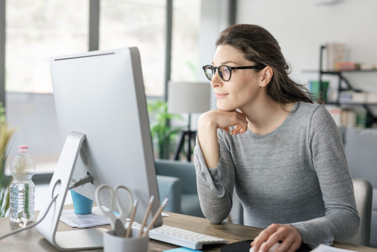 Femme assise derrière un bureau et regardant un écran d'ordinateur