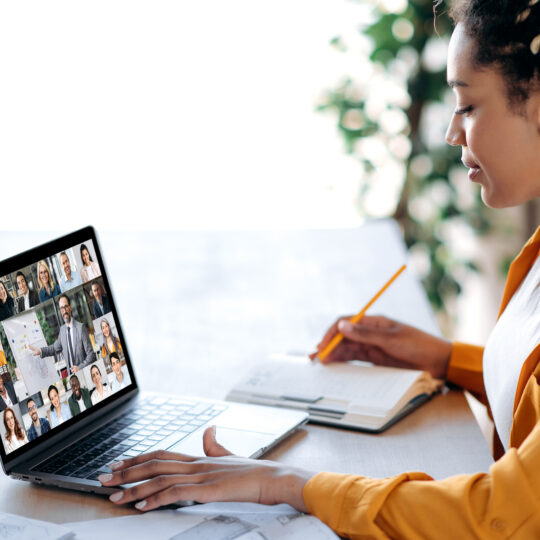 Femme assise derrière un bureau en train de visionner un webinar sur son écran d'ordinateur