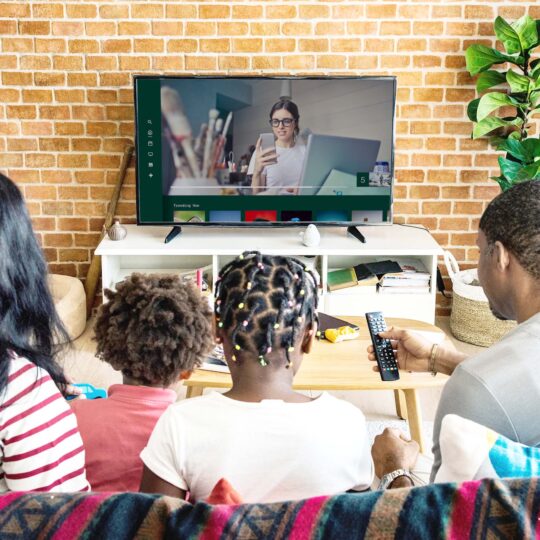 Famille assises sur un canapé regardant un contenu de TV en streaming sur leur TV connectée (CTV)