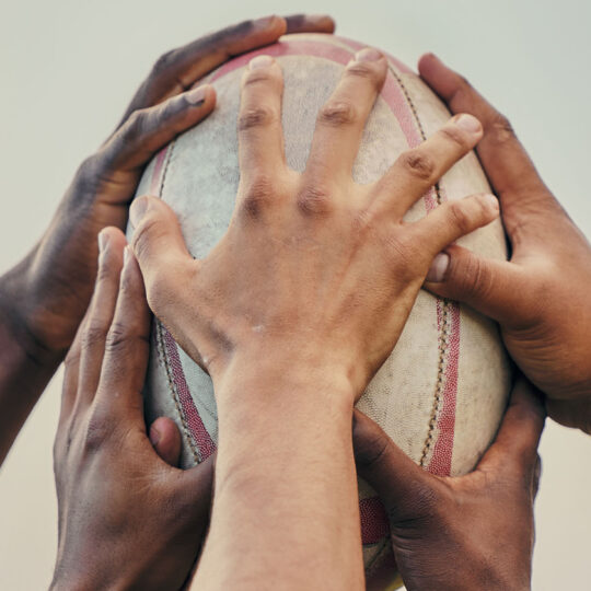 Hands grabbing rugby ball