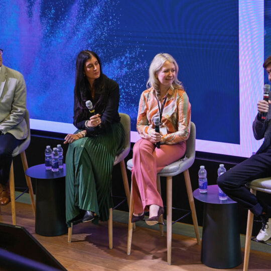 Picture of a panel of people sitting in chairs on a stage
