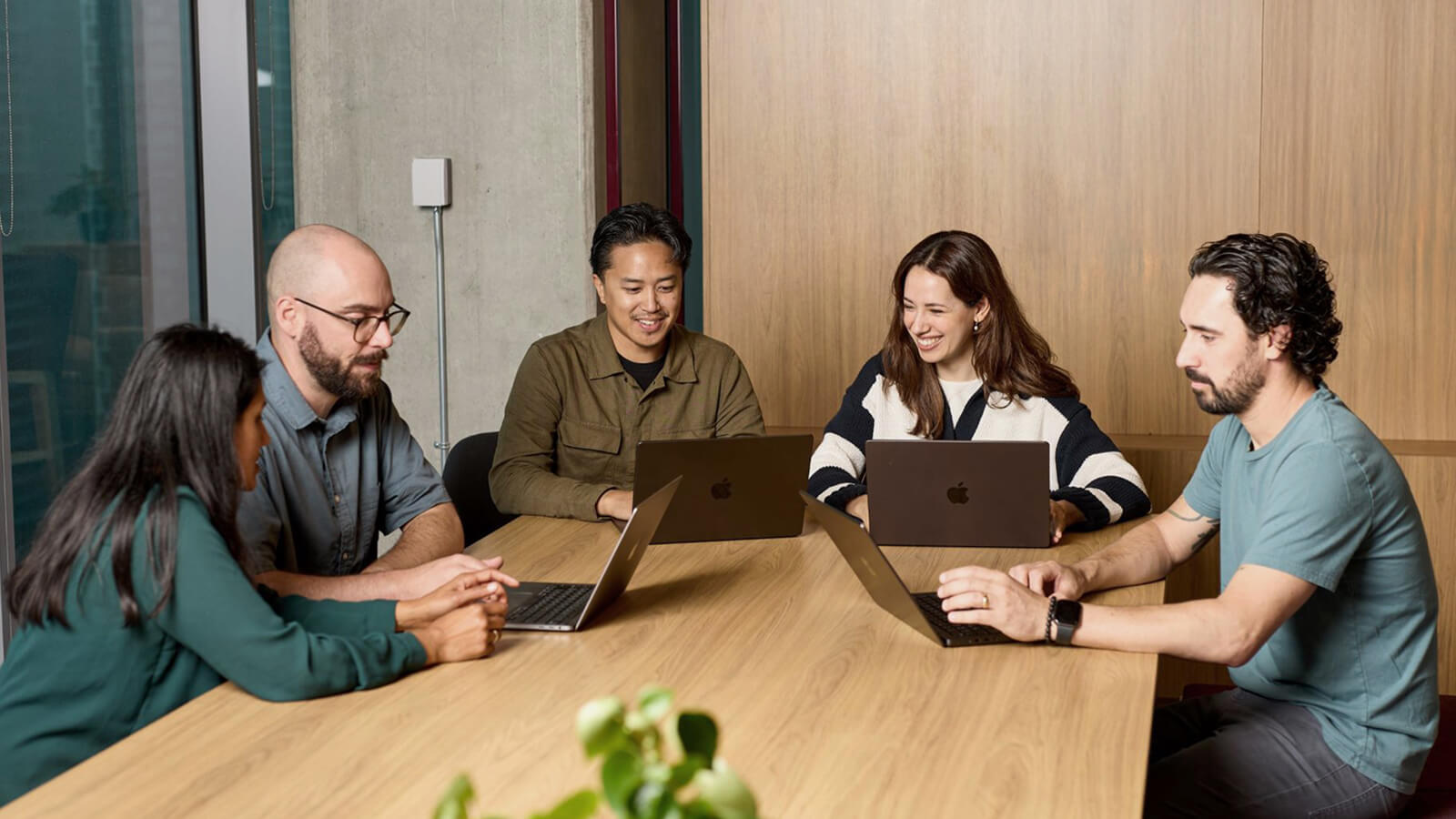 People sitting around a meeting table on laptops